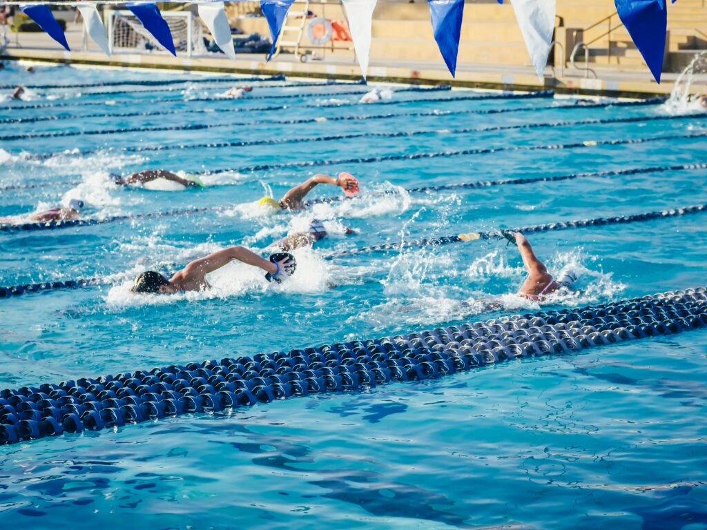 Group of swimmers competing in an outdoor pool, showcasing athletic endurance and technique.